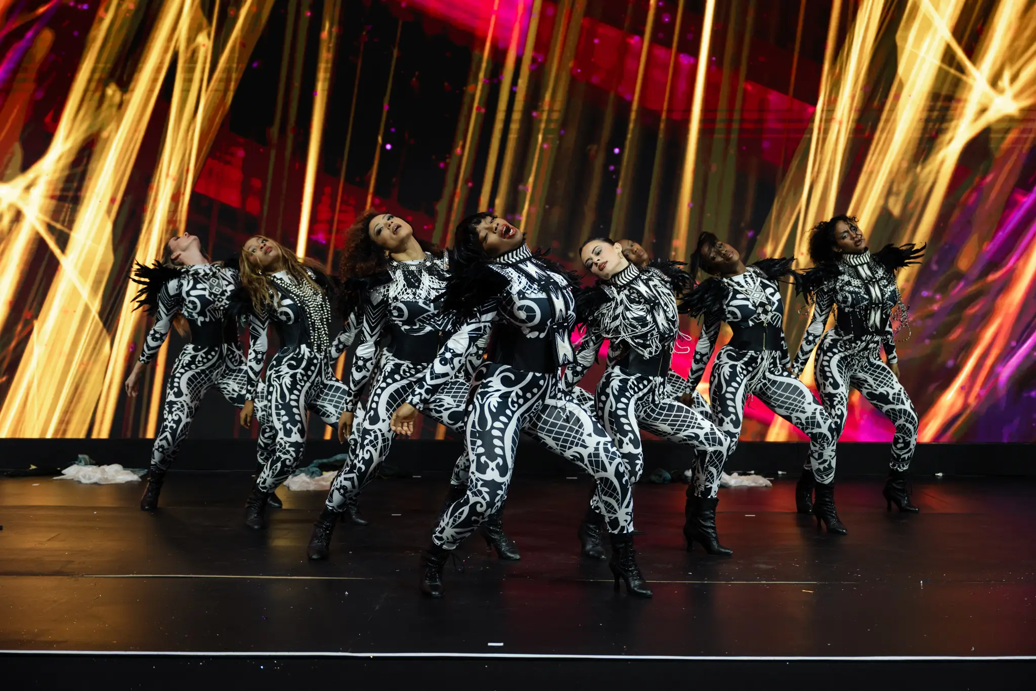 Dancers performing on a stage lit with gold and pink light